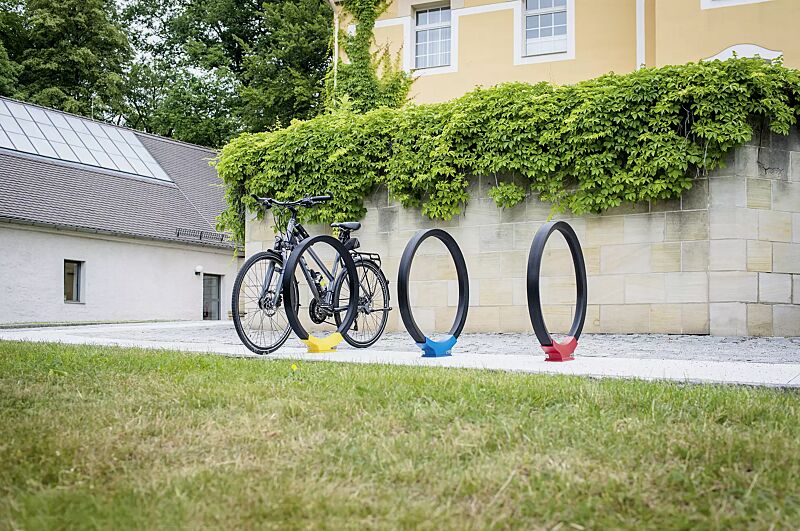 anlehnbuegel-gomez__shoKAT0057833 Anlehnbügel GOMEZ, Aluminiumfußabdeckung in RAL 1021 rapsgelb, RAL 5019 capriblau und RAL 3020 verkehrsrot