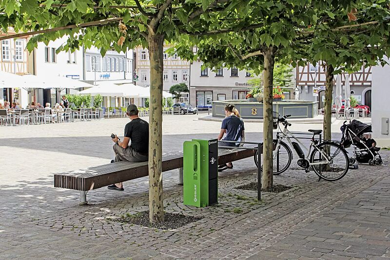 fahrrad-abstellanlage-velo-connector__shoKAT0071222 Fahrrad-Abstellanlage VELO-CONNECTOR mit Ladeschließfach und Radeinstellung links, Stahlteile in RAL 7016 anthrazitgrau / RAL 6018 gelbgrün, Anlehnbügel TAMORES zum Einbetonieren in RAL 7016 anthrazitgrau und Sitzbank WOODY ohne Rückenlehne