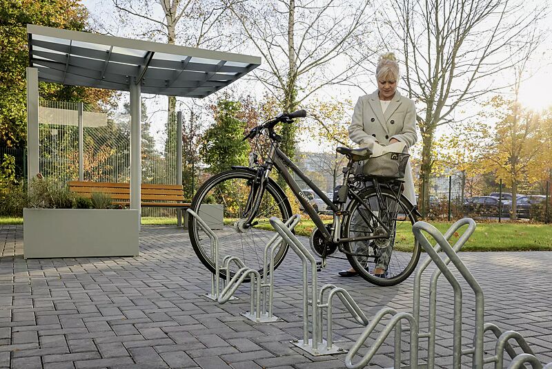 fahrradstaender-hervey__shoKAT0068190 Einzelfahrradständer HERVEY zum Aufdübeln, Meeting-Point PIN, Dachbreite x Dachtiefe 3075 mm x 3075 mm, mit Windschutzwand PIN SCREEN, Sitzbank NATURA, Abfallbehälter LACES, Pflanzbehälter MALOUT, Stahlkonstruktion in RAL 7046 telegrau