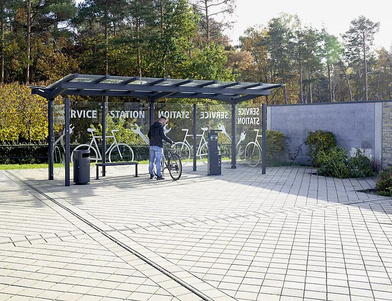 fahrradueberdachung-tucana__shoKAT0065901 Fahrradüberdachung TUCANA, Dachbreite x Dachtiefe 6300 mm x 4600 mm, Rück- / Seitenwände ESG, Klarglas, Sitzbank RIMINI, Fahrradanlehnbügel FLINT, Servicestation ASSIST PREMIUM, Abfallbehälter CIMA, Stahlkonstruktion in RAL 7016 anthrazitgrau