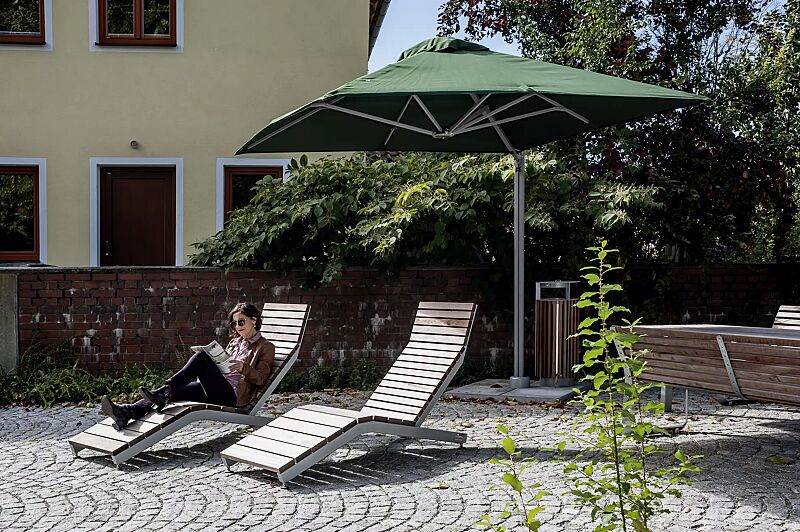 freiarmschirm-single-pole__shoKAT0056365 Freiarmschirm SINGLE POLE, quadratisch, zum freien Aufstellen, Fliesen bauseits, in olive green sowie Liegebank RIVAGE und Abfallbehälter DIAGONAL