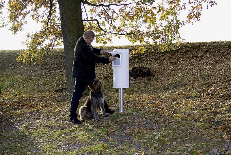 Beutel entnehmen, Hundekot mit umgestülptem Beutel aufnehmen und zuknoten