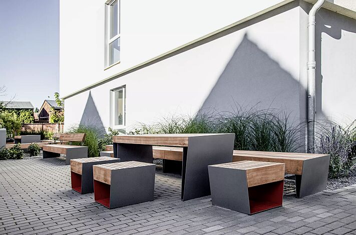 Sitz BLOCQ mit Jatobaholzbelattung, Stahlteile in bicolour (Sonderausführung in RAL 9007 graualuminium und RAL 3020 verkehrsrot), Sitzbank BLOCQ und Tisch BLOCQ (Sonderausführung)