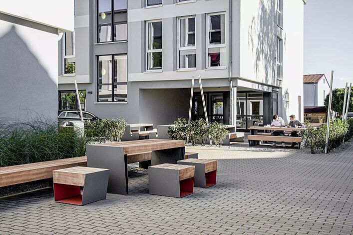 Sitz BLOCQ mit Jatobaholzbelattung, Stahlteile in bicolour (Sonderausführung in RAL 9007 graualuminium und RAL 3020 verkehrsrot), Sitzbank BLOCQ und Tisch BLOCQ (Sonderausführung)