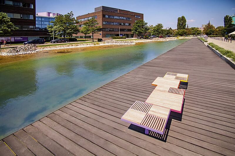 Sitz PIXEL CITÉ, bestehend aus verschiedenen Segmenten, mit Robinienholzbelattung, Stahlteile in RAL 2004 reinorange, RAL 3020 verkehrsrot, RAL 4010 telemagenta, RAL 4005 blaulila und RAL 1021 rapsgelb