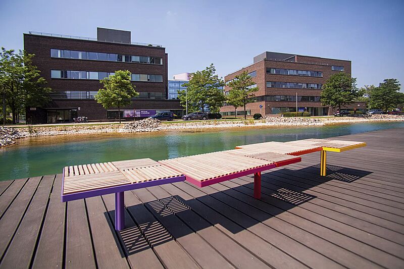 Sitz PIXEL CITÉ, bestehend aus verschiedenen Segmenten, mit Robinienholzbelattung, Stahlteile in RAL 2004 reinorange, RAL 3020 verkehrsrot, RAL 4010 telemagenta, RAL 4005 blaulila und RAL 1021 rapsgelb