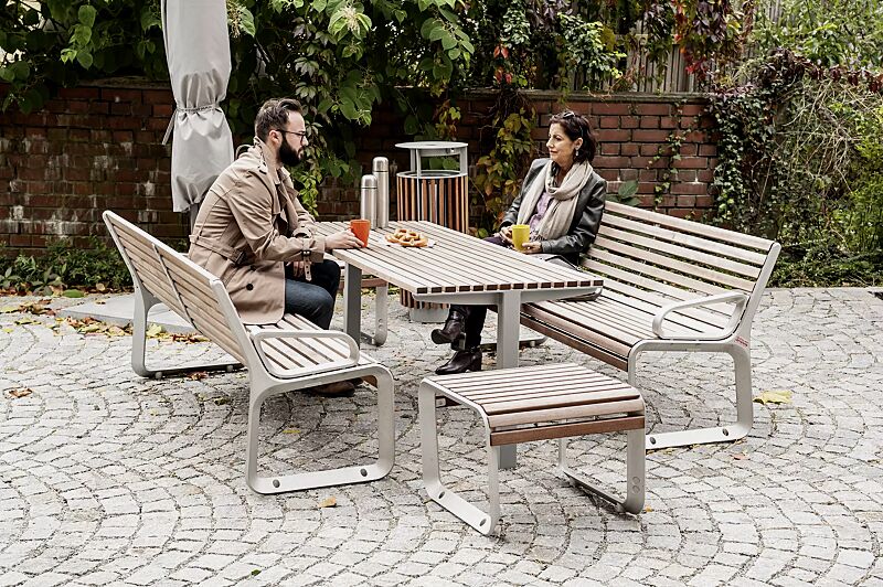 sitzbank-portiqoa__shoKAT0056344 Sitzbank PORTIQOA mit Rückenlehne und Armlehnen und Sitz PORTIQOA ohne Rückenlehne, mit Jatobaholzbelattung sowie Tisch UNI ONE, Abfallbehälter DIAGONAL und Freiarmschirm SINGLE POLE