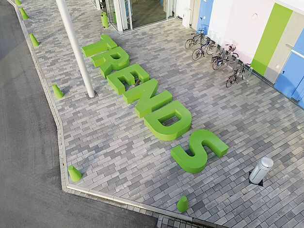 Sitzbuchstaben LETTER LINE in RAL 6037 reingrün sowie Poller KONE