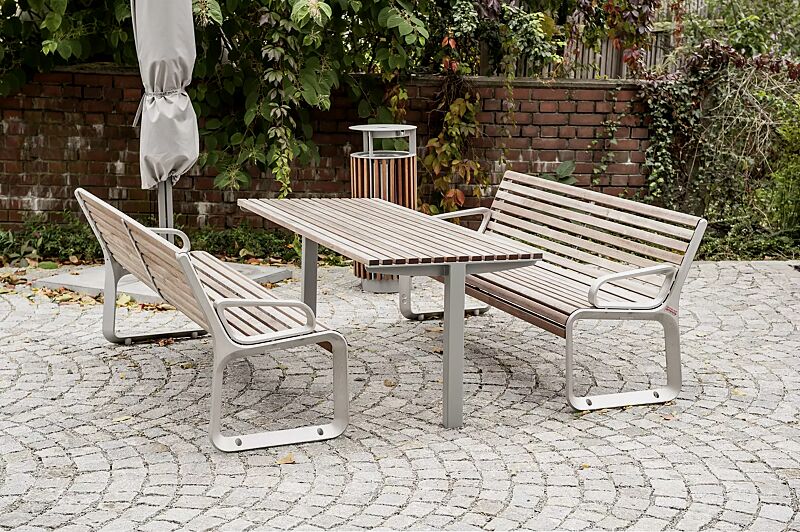 Tisch UNI ONE mit Jatobaholzbelattung, Stahlteile in RAL 9006 weißaluminium und Sitzbank PORTIQOA sowie Abfallbehälter DIAGONAL