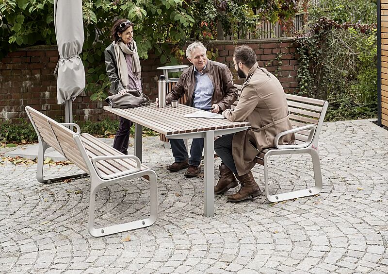 Tisch UNI ONE mit Jatobaholzbelattung, Stahlteile in RAL 9006 weißaluminium und Sitzbank PORTIQOA sowie Abfallbehälter DIAGONAL