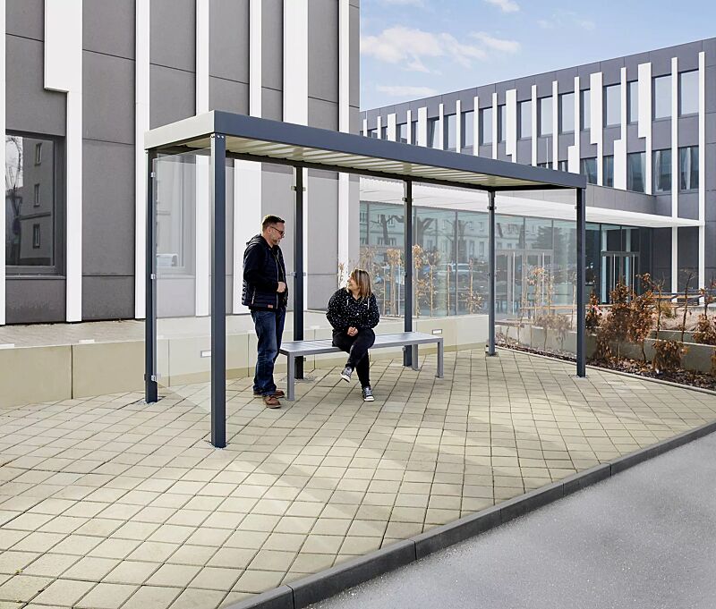 Wartehalle GEMALA, Dachbreite x Dachtiefe 4600 mm x 1600 mm, mit Rück- / Seitenwände ESG, Klarglas sowie Sitzbank LIGURIA, Stahlkonstruktion in RAL 7016 anthrazitgrau