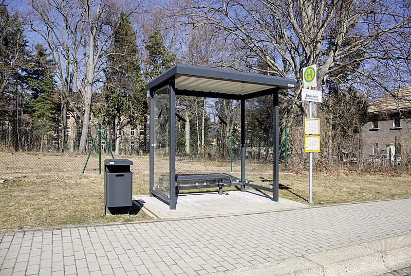 Wartehalle STADT, Dachbreite x Dachtiefe 3620 mm x 1800 mm, Rück- / Seitenwände ESG, Klarglas mit Raubvogelaufkleber, Sitzbank SESTO, Abfallbehälter HALIFAX, Stahlkonstruktion in RAL 7021 schwarzgrau