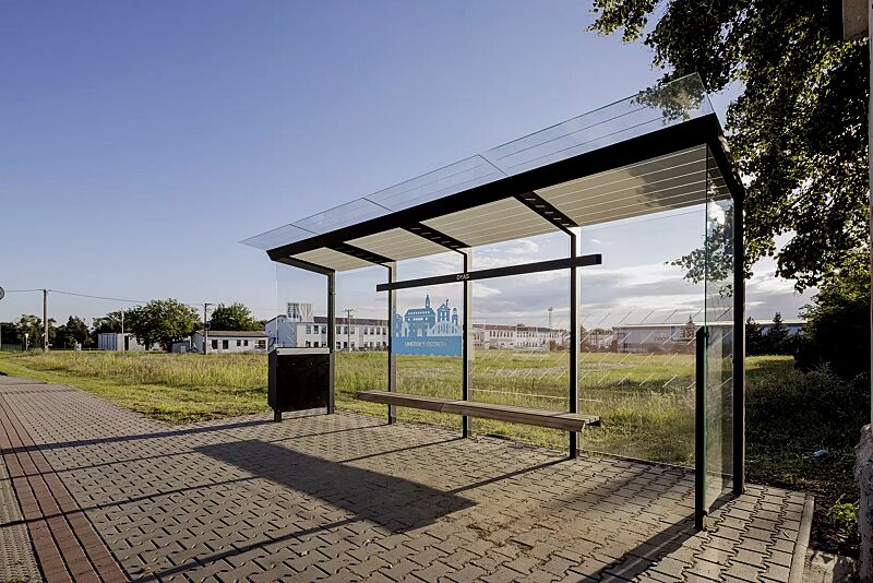 wartehalle-traxo__shoKAT0073438 Wartehalle TRAXO, Dachbreite x Dachtiefe 5560 mm x 1740 mm, Rück- / Seitenwand ESG, Klarglas, mit Siebdruckdekor und bauseitiger Beklebung sowie Werbevitrine, Abfallsammler (auftragsbezogen), Sitzbank Thermoholz Esche, Stahlkonstruktion in RAL 9005 tie...